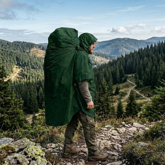 Load image into Gallery viewer, Hiker wearing a green waterproof poncho over a large pack in a mountain valley