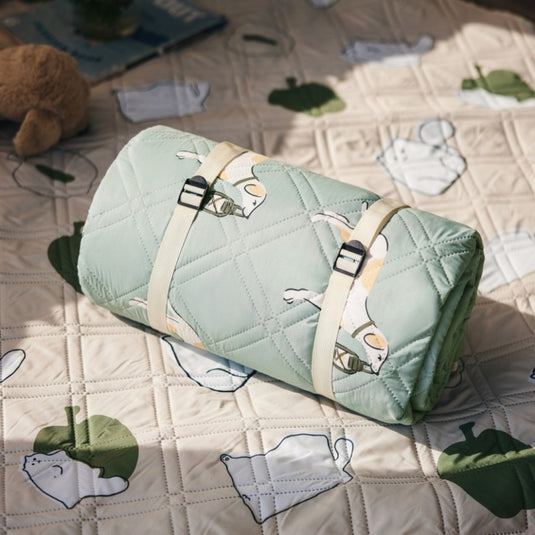 Compact green Naturehike picnic blanket rolled with off-white straps and buckles
