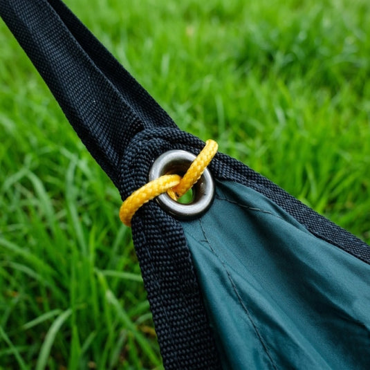 Detail of a durable metal grommet and webbing for secure camping tarp tension.
