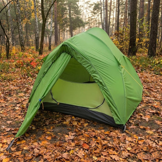 Green Ligera 2 tent with open entrance on autumn leaves in a pine forest setting