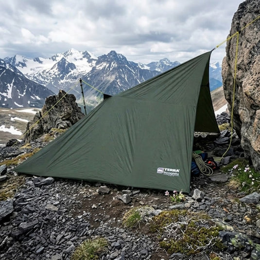 Waterproof mountain shelter tarp secured with guy lines in rocky terrain