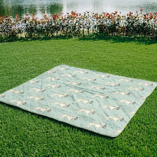 Quilted waterproof picnic mat with dog pattern on green grass near a pond