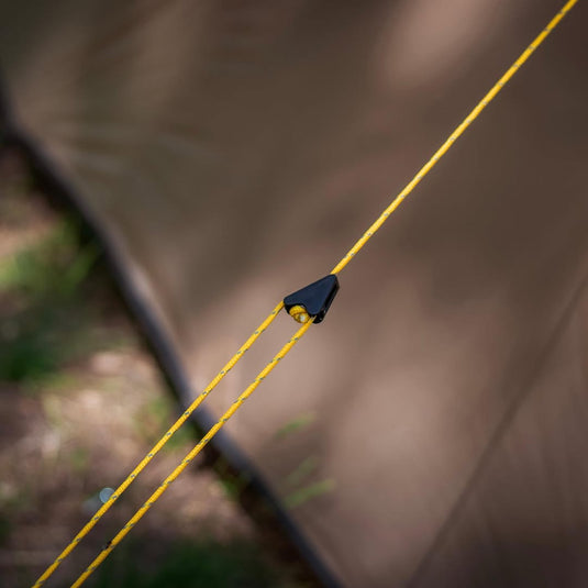 Close-up of yellow reflective guyline with plastic tensioner on an Alfa 3 tent