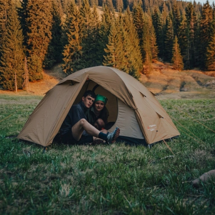 Load image into Gallery viewer, Two campers sitting inside Omega 3 sand tent in a pine forest clearing
